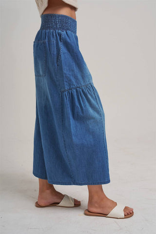 Blue denim skirt worn by a person on a plain background