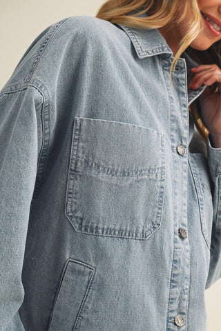 Close-up of a person wearing a light blue denim shirt with a neutral background