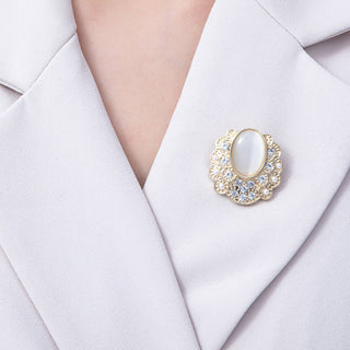 Gold brooch with gemstones on a white blazer