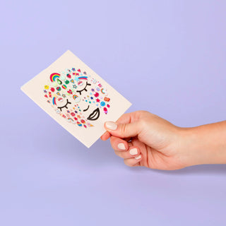 Hand holding a card with colorful designs on a purple background