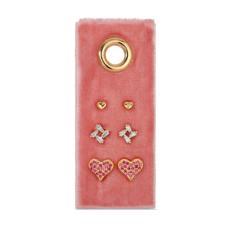 Set of earrings on a pink velvet card with gold and gemstone designs.