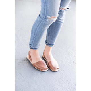 Person wearing light blue ripped jeans and open-toe sandals on a white floor.
