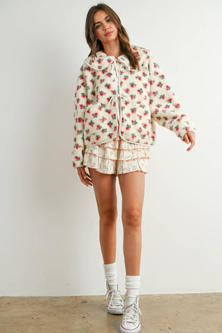 Woman wearing a floral outfit with shorts and sneakers on a plain background