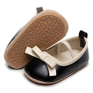 Black baby shoes with a bow on a white background