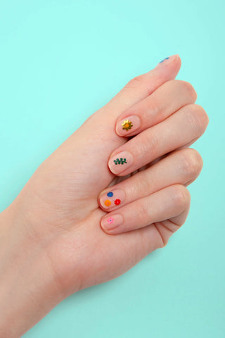 Hand with colorful nail art on a light blue background
