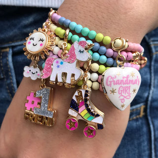 Colorful beaded bracelet with various charms on a wrist against a denim background