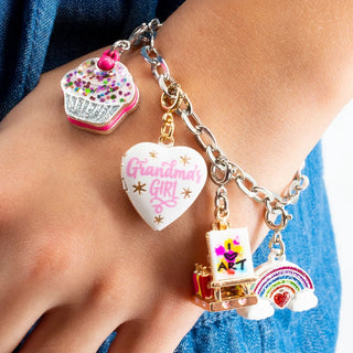 Hand wearing a colorful charm bracelet with various charms against a blue denim background
