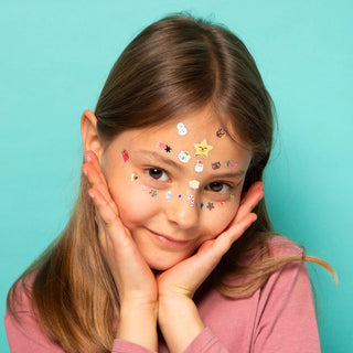 Young girl with stickers on her face against a teal background