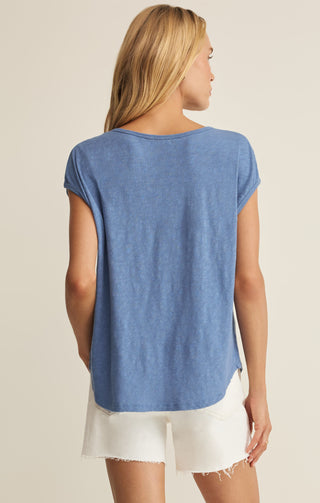 Woman wearing a blue sleeveless top and white shorts on a beige background