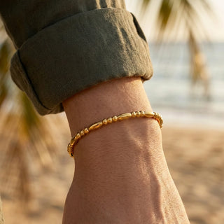 Gold bracelet on a wrist with blurred natural background