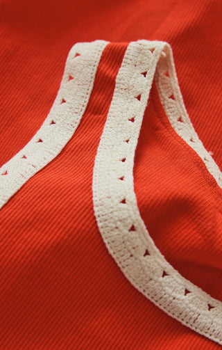 Close-up of a red garment with white lace trim