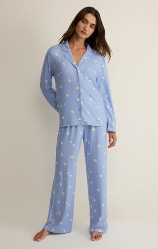 Woman wearing a blue pajama set with a subtle pattern on a beige background