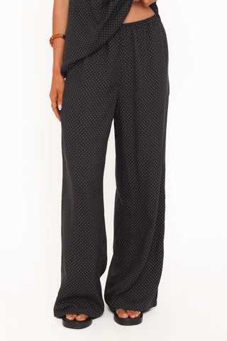 Black wide-leg pants with a small white polka dot pattern, shown on a model from the waist down against a white background.