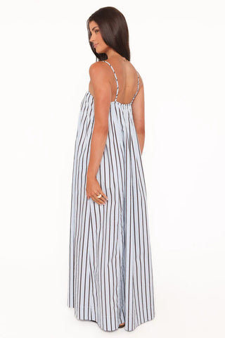 Woman wearing a long white dress with black stripes on a white background