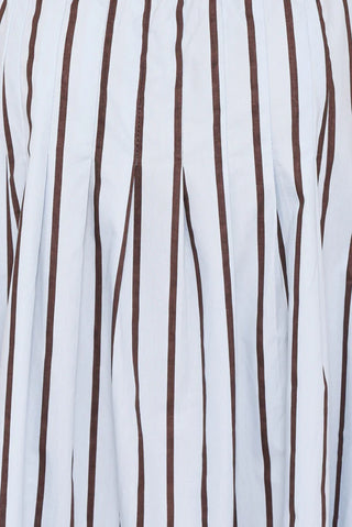 A close-up of a white pleated fabric with vertical dark brown stripes.