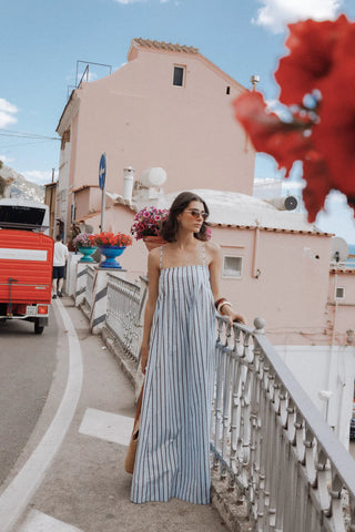 Woman in a long dress standing on a bridge with a scenic background