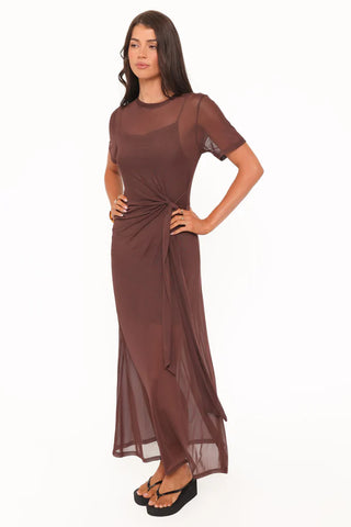 Woman wearing a brown dress with sheer sleeves on a white background