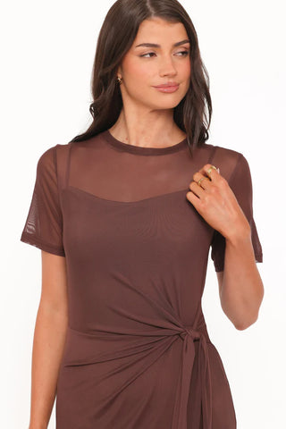 A woman wearing a brown short-sleeve knit dress with a sheer mesh yoke and a twisted waist detail, shown against a plain white background.