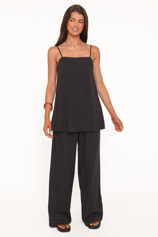 Woman wearing a black polka dot top and wide-leg pants on a white background