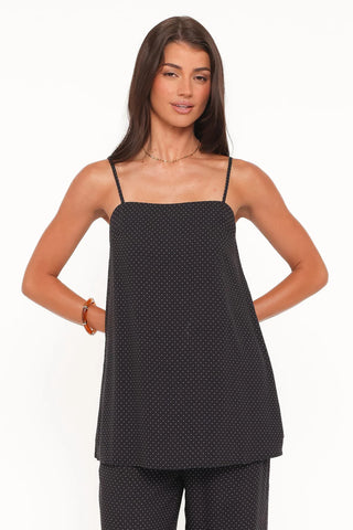 Woman wearing a black polka dot top and pants on a white background