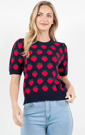 Woman wearing a navy sweater with red heart patterns and light blue jeans on a white background