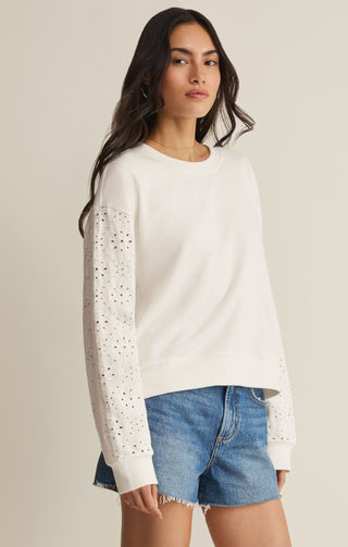 woman wearing long sleeve tee shirt that is white and has eyelet sleeves