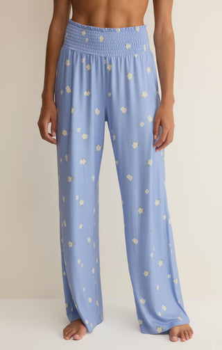 Woman wearing blue smocked loungewear pants with flowers on them 