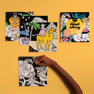 Coloring books with animal illustrations on a yellow background, one book open with a hand coloring.
