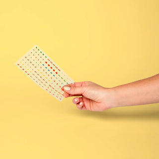 Hand holding a small keyboard-style chart against a yellow background